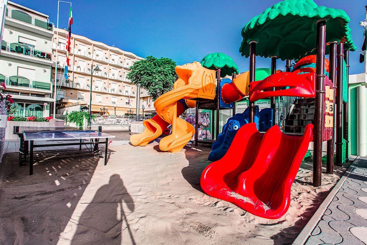 Spielplatz im Sand mit bunten Rutschen und Tischtennisplatte